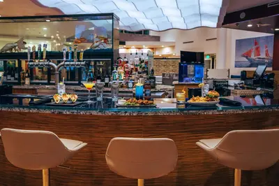 a bar with three chairs in front of a bar at Maritime Hotel Fort Lauderdale Airport & Cruiseport in Fort Lauderdale