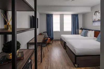 a hotel room with two beds and a desk at Generator Miami in Miami Beach