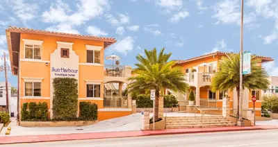 a orange building with palm trees in front of it at Sun Harbour Boutique Hotel in Miami Beach