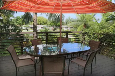 a table and chairs under an umbrella on a deck at The Cabanas Guesthouse & Spa - Gay Resort catering to Gay Men in Fort Lauderdale