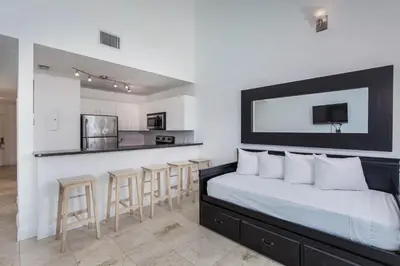 a bedroom with a large bed and a kitchen at New Point Miami Beach Apartments in Miami Beach
