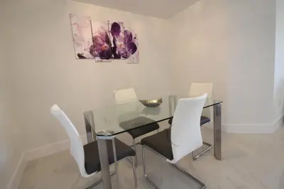 a glass table with white chairs and a painting at Yacht Club at Aventura 1 Bd 1 Bth Brand New in Aventura