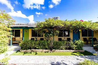 a yellow house with a green door and some bushes at The Desoto - Oceanview Inn in Hollywood