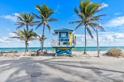 a life guard tower on a beach with palm trees at The Desoto - Oceanview Inn in Hollywood
