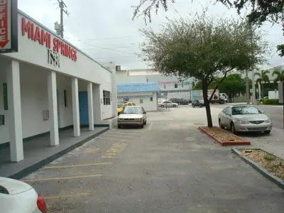 a parking lot with cars parked in front of a pharmacy at Miami Springs Inn in Miami