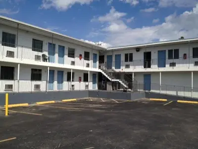 a large white building with blue windows and a parking lot at Miami Springs Inn in Miami