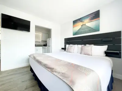 a bedroom with a large white bed with a tv on the wall at Ocean Villas in Hollywood