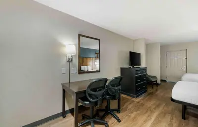 a hotel room with a desk and a bed and a mirror at Extended Stay America Suites - Miami - Airport - Doral in Miami