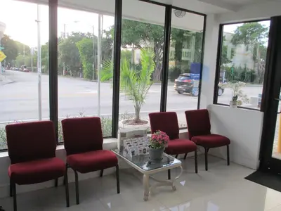 a waiting room with red chairs and a table and windows at Shalimar Motel in Miami