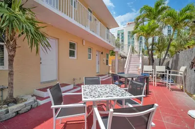 a patio with tables and chairs and palm trees at Laguna Blu Beach in Hollywood