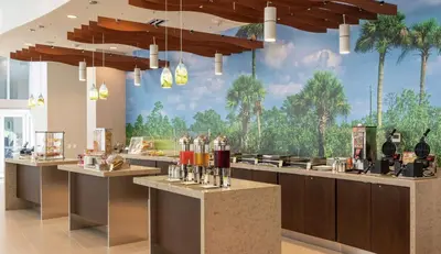 a bar with a mural of palm trees on the wall at DoubleTree by Hilton Miami Doral in Miami