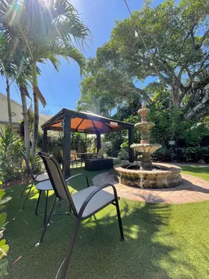 a patio with a fountain with a chair and a table at Sheridan Hostel in Dania Beach