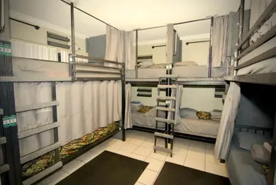 a room with three bunk beds and a ladder at Sheridan Hostel in Dania Beach