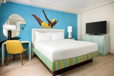 a hotel room with a bed and a mirror at Hotel Continental Miami Beach, Tapestry Collection by Hilton in Miami Beach