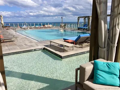 a swimming pool with chairs and the ocean in the background at Rent in LYFE Resort in Hollywood