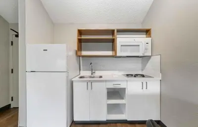 a small kitchen with white cabinets and a white refrigerator at Extended Stay America Premier Suites - Miami - Airport - Miami Springs in Miami