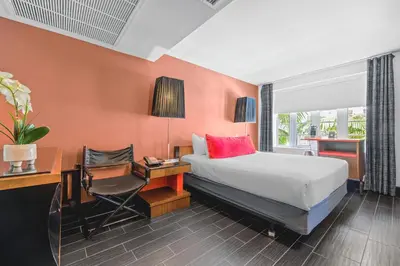 a bedroom with a bed and a desk with a chair at The Fairwind Hotel in Miami Beach