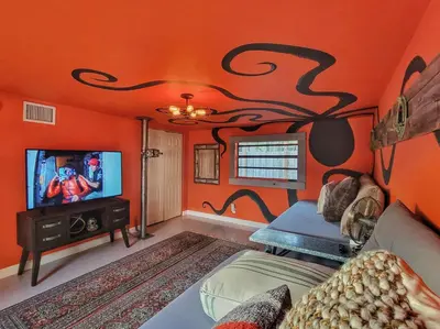 a living room with orange walls and a tv at The Captain's Quarters - Home & Guesthouse in Fort Lauderdale