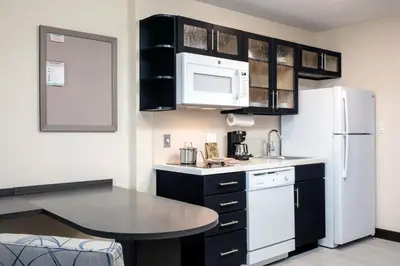 a kitchen with black cabinets and a white refrigerator at Candlewood Suites - Miami Exec Airport - Kendall by IHG in Kendall