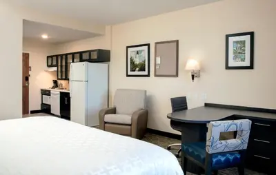 a hotel room with a bed and a desk and a kitchen at Candlewood Suites - Miami Exec Airport - Kendall by IHG in Kendall