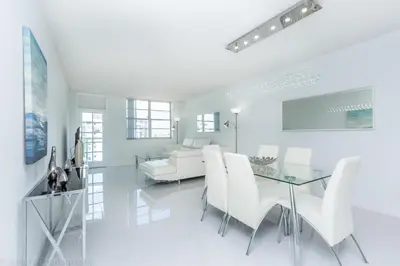 a white dining room with a glass table and white chairs at Ocean Reserve Sunny Isles in Miami Beach