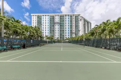 a tennis court in front of a large building at Ocean Reserve Sunny Isles in Miami Beach