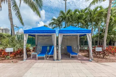 a blue tent with blue chairs and palm trees at Ocean Reserve Sunny Isles in Miami Beach