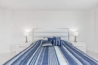 a large bed with blue and white sheets and pillows at Ocean Reserve Sunny Isles in Miami Beach