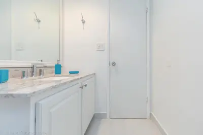 a white bathroom with white cabinets and mirrors at Ocean Reserve Sunny Isles in Miami Beach
