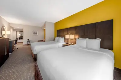 a hotel room with two beds and a yellow wall at Comfort Suites Miami Airport North in Miami