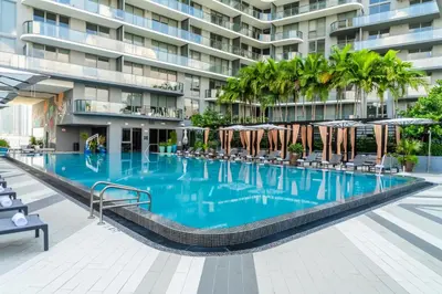 a swimming pool with chairs and umbrellas in front of a building at Hyde Suites Midtown Miami in Miami