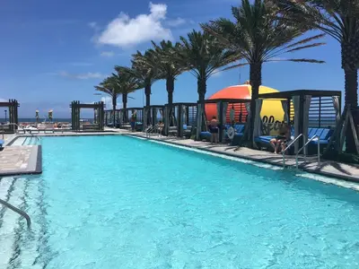 a swimming pool with palm trees and a playground at Lyfe Residence Building - Private apts over the beach in Hollywood