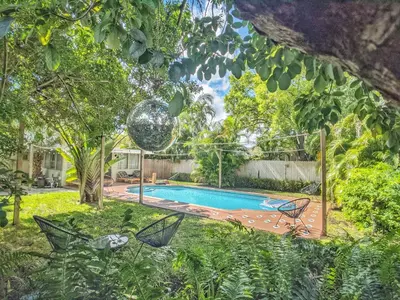 a backyard with a swimming pool and trees at Casa del Ojo- Heated Pool - 3 King beds in Fort Lauderdale