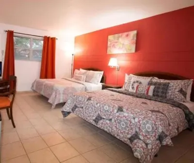a bedroom with two beds and a red wall at Gables Inn in Miami