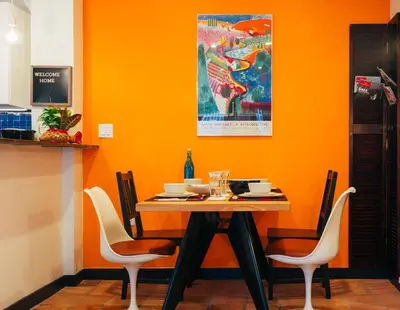 a dining room with an orange wall and a table and chairs at Renovated Historic Coconut Grove Cottage Home in Miami