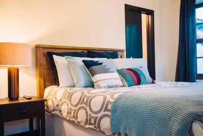 a bedroom with a bed with pillows and a lamp at Renovated Historic Coconut Grove Cottage Home in Miami
