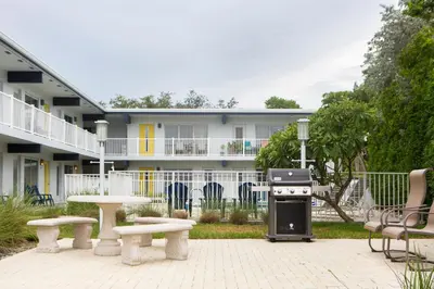 a grill and benches in front of a building at Lovely apartment on the canal with a pool in Fort Lauderdale