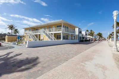 a building on a beach with palm trees and a sidewalk at Paradise Oceanfront by HBH in Hollywood