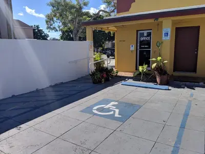 a handicapped parking sign on a sidewalk in front of a building at Ramona Motel in Miami