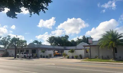 a white building with a truck parked in front of it at Ramona Motel in Miami