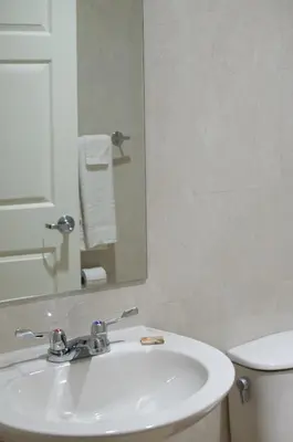 a bathroom with a sink and a mirror and a toilet at Carl's El Padre Motel in Miami