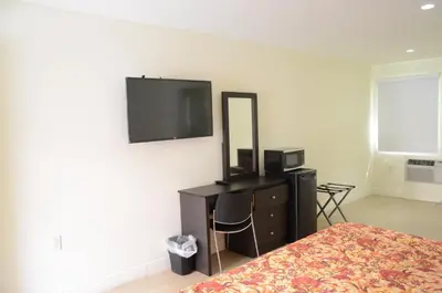 a bedroom with a bed and a dresser and a mirror at Carl's El Padre Motel in Miami