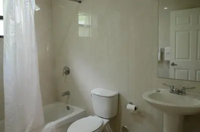 a white bathroom with a toilet and a sink at Carl's El Padre Motel in Miami
