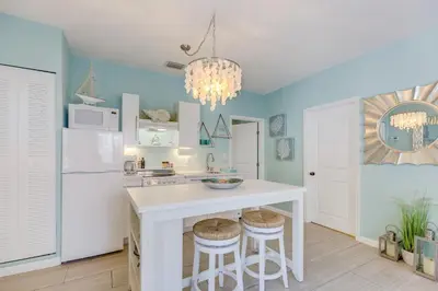 a kitchen with blue walls and a white island with stools at A Suite Retreat in Miami