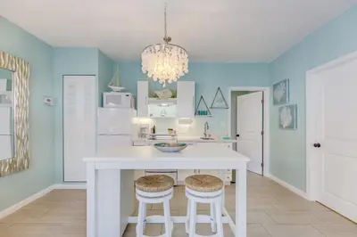 a kitchen with a white island with two stools at A Suite Retreat in Miami