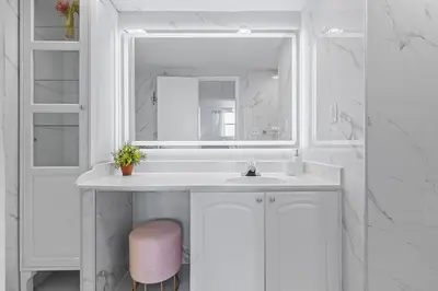 a white bathroom with a sink and a pink stool at Great Apartment with beach access in Hollywood