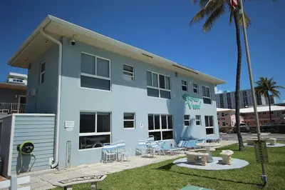 a white building with chairs and a palm tree at Shore View Hotel in Hollywood