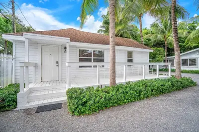 a white house with a porch and palm trees at Grove Bay Bungalow - 2/2 Gated Cottage-Walk to Bay in Miami
