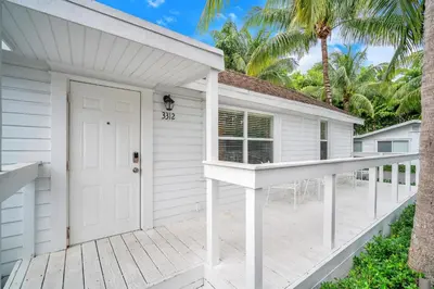 a white house with a white door and a porch at Grove Bay Bungalow - 2/2 Gated Cottage-Walk to Bay in Miami
