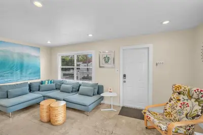 a living room with a blue couch and a chair at Grove Bay Bungalow - 2/2 Gated Cottage-Walk to Bay in Miami